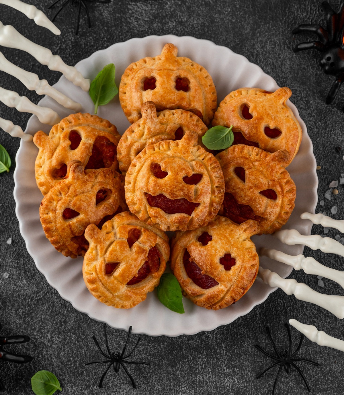 plate full of mini jack-o-lantern hand pies on a white plate, Mini hand pies with fruit filling.