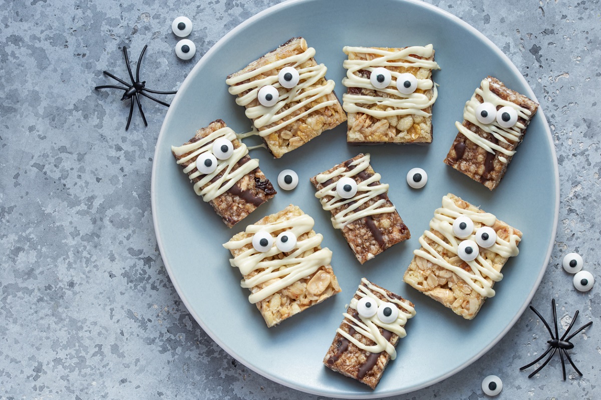 granola bars and rice krispy treats made to look like mummies using a drizzle of white chocolate and candy eyes