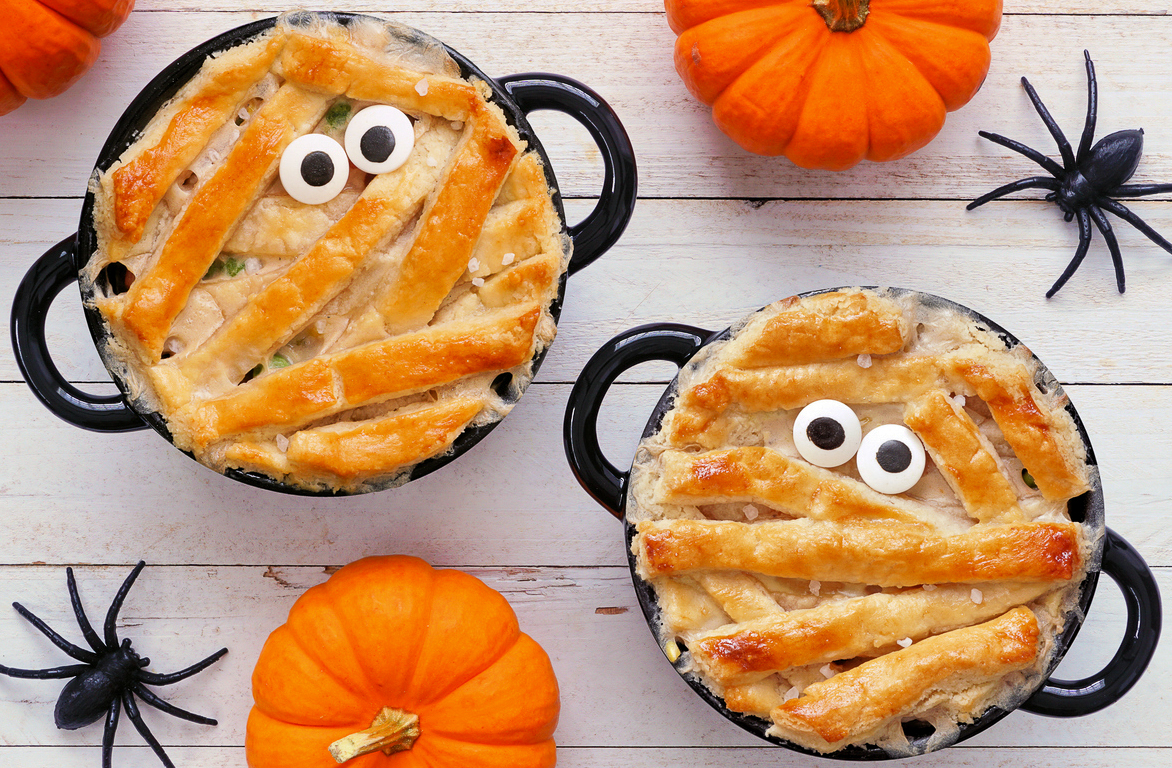mini chicken pot pies in black soup crocks pie dough cut and baked in strips to make them look like a mummy for Halloween Party Food. Garnished with 2 candy eyes.