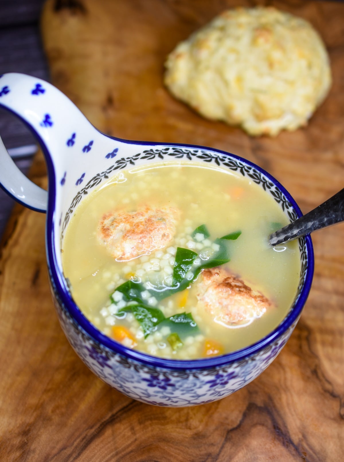 chicken pastina soup with mini chicken meatballs shown in a Polish pottery soup bowl with curved handle that is white with blue accents.